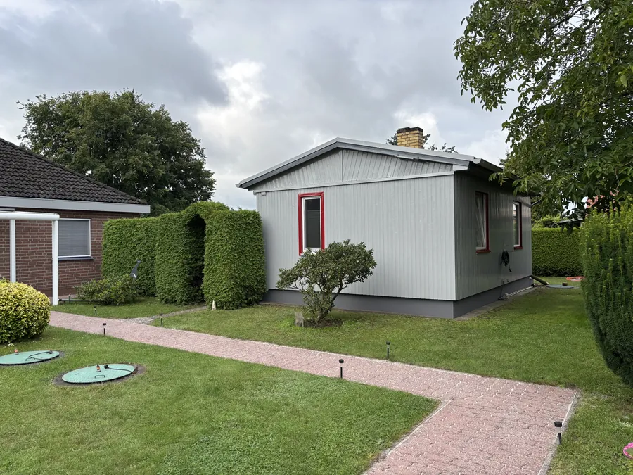Grauer Bungalow in einem Garten nach dem Außenanstrich