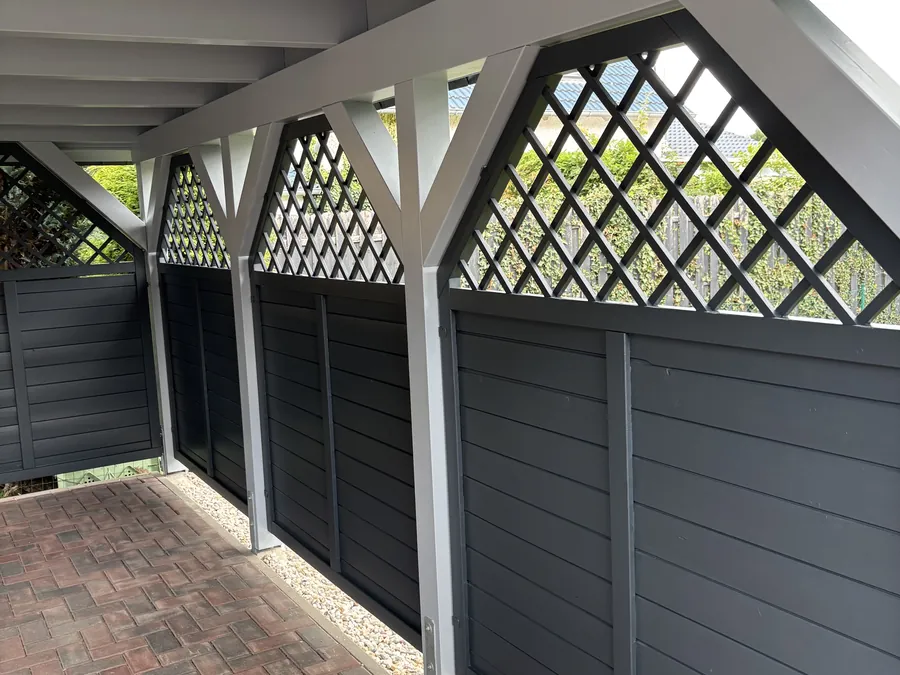Carport mit anthrazitfarbenen Paneelen und weißem Rankgitter