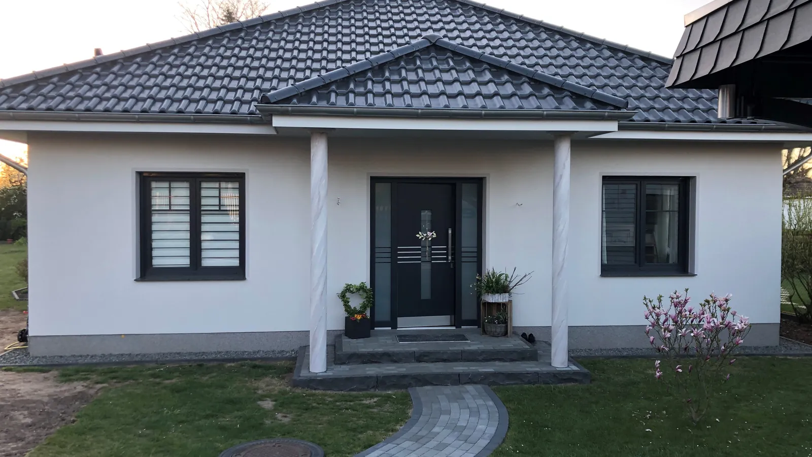 Bungalow mit weißer Fassade und überdachtem Eingang nach dem Anstrich