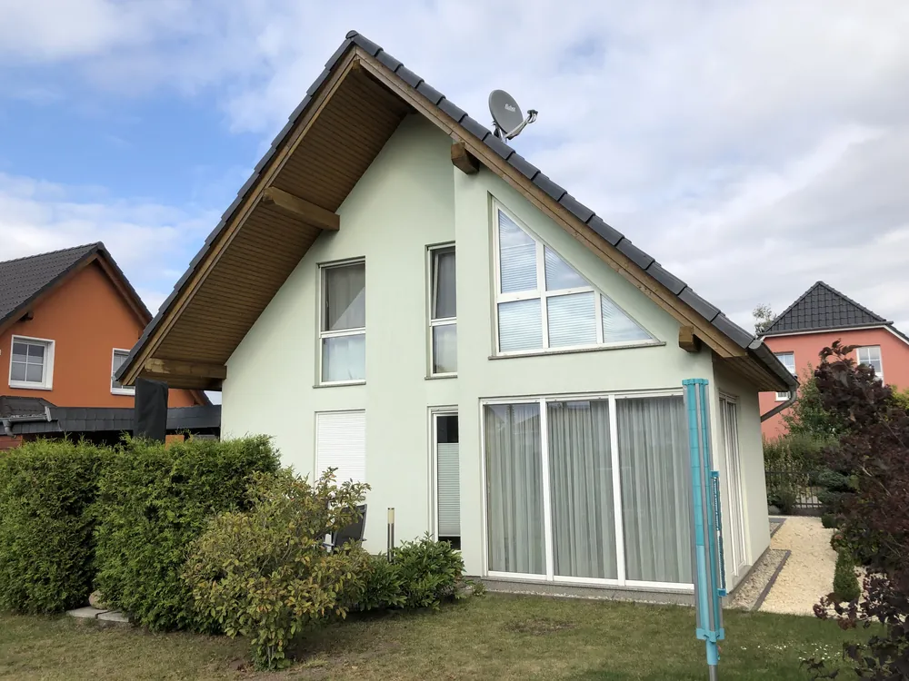 Einfamilienhaus mit hellgrün gestrichener Fassade und Holzgiebel